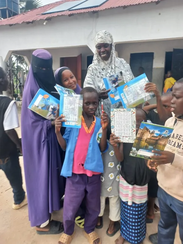 Fatou Sanyang mit Kindern, die neue Schulhefte zeigen